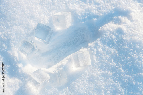 Foto Imprint from the bottle on the fluffy, snowy surface with sunlight surrounded by ice cubes