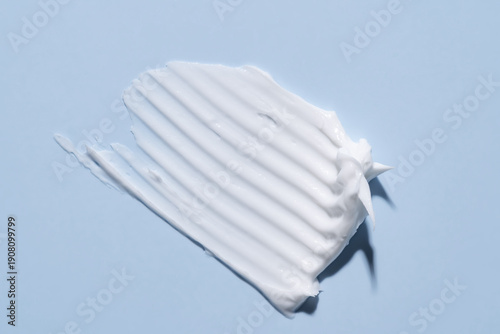 White cosmetic cream texture, skincare lotion swatch on light blue background. Face creme, body moisturizer, hair conditioner smear smudge stroke. Creamy beauty product closeup