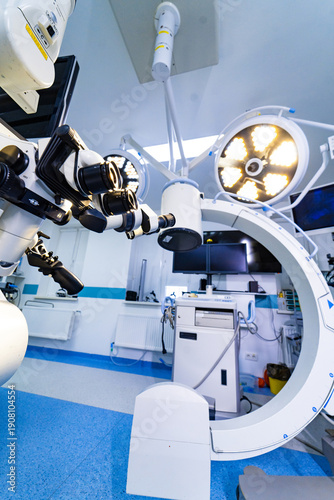 Operating room with neurosurgery microscope and overhead surgical lights. Wide shot of neurosurgical microscope integrated with large circular LED surgical lamps.