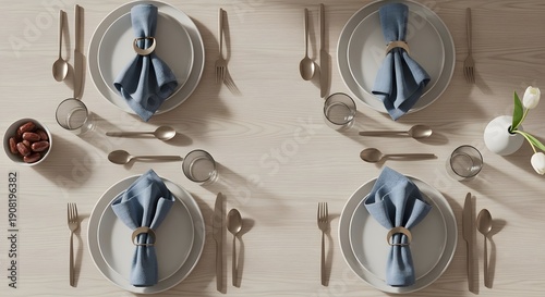 Table setting with silverware and blue napkins on white plates, viewed from above, in a minimalist dining environment.