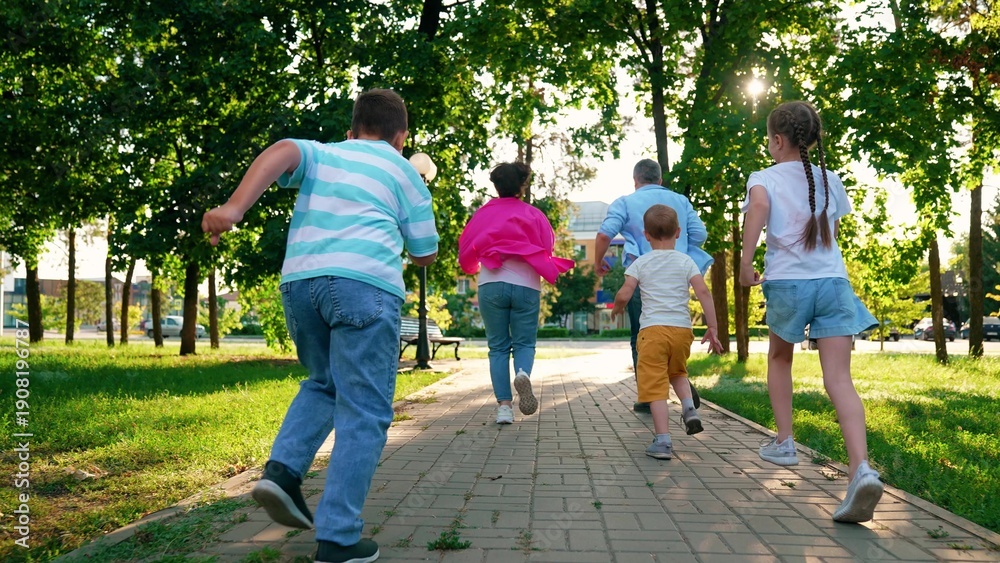 Obraz premium Family playing in city park. Parents, kids boys play running in city park summer. Dad mom, sons children having fun run city street. Concept parenting. Happy family. Happy people dad mom son, daughter