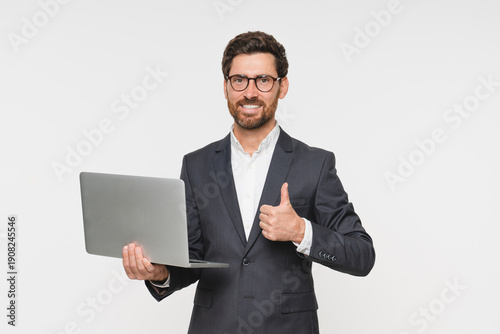 Slika na platnu Satisfied male business coach in suit holding laptop showing thumb up for review opinion, approving good device quality, portrait for winning, online success and thank you isolated white background