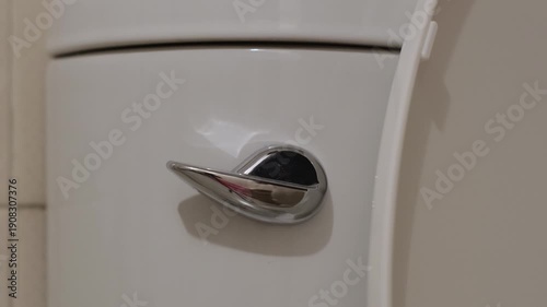 Finger pressing a toilet flush lever creating a mechanical clunk and rushing water sound