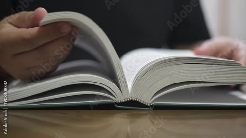 Hand flipping through book pages and closing it shut creating a soft paper rustling and thudding sound