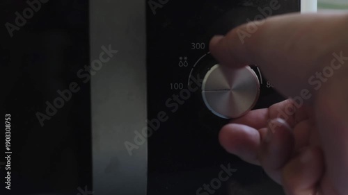 Hand turning a microwave power dial creating multiple mechanical clicking sounds