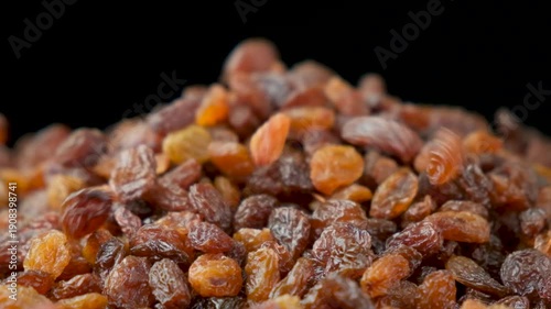 Brown raisins poured slow motion, macro food background