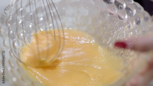 Close-up of Hand Beating Egg Mixture with Whisk in a Glass Bowl for Baking