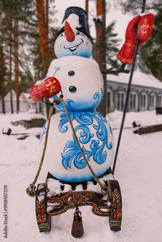 figure of a snowman on a sled in a snow-covered park