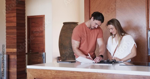Couple in kitchen signing lease together for new apartment, smiling