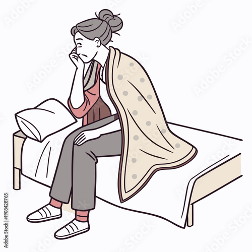 Woman sitting on bed with blanket wrapped around shoulders looking unwell