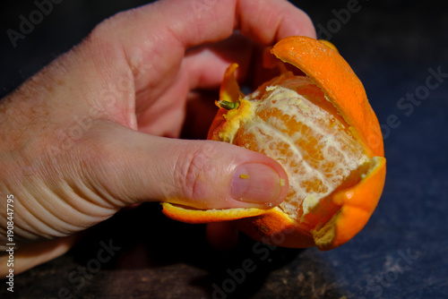 Orange beim schälen in der hand