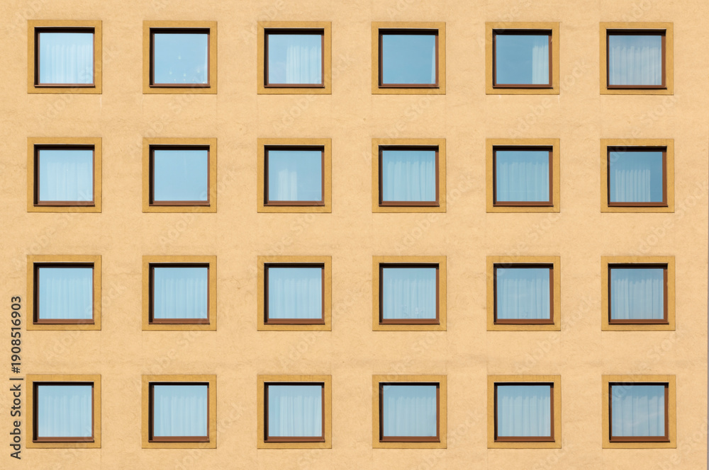 Obraz premium Multiple square windows of a residential flat apartment building from the font with yellow walls, abstract modern architecture exterior, minimal ist urban style