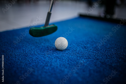 The image shows a mini golf set, a miniature version of golf focused exclusively on putting. The set includes specialized putters and lightweight golf balls designed for artificial turf or indoor play