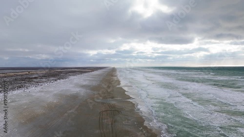 Caspian Sea coastline near Aktau, Mangystau region, Kazakhstan, captured in a top-down aerial drone shot featuring powerful green-blue sea waves rolling onto an empty yellow-brown sandy shore. Winter 