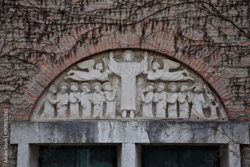 Cuadro en lienzo Stone relief above brick church portal depicting Christ with angels and disciples in traditional Christian iconography