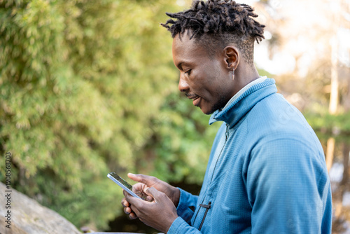 African American man wirelessly connecting in a park, enjoying modern technology outdoors