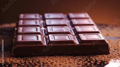 Closeup of a tempting dark chocolate bar, dusted with cocoa. Delicious treat.