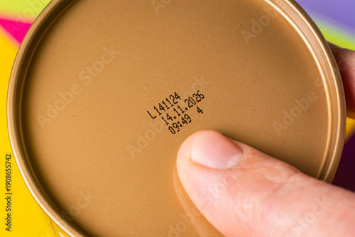 Фотография A man checks the production date and expiration date of a product on a can with his index finger