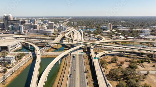 A high-altitude aerial view highlights the intersection of modern infrastructure and skyline in downtown Orlando.