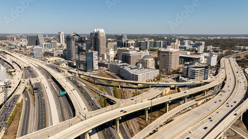 An aerial perspective captures downtown Orlando’s skyline framed by the sweeping curves of the I-4 and SR-408 interchange.