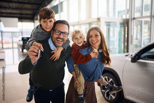 Cuadro en lienzo Cheerful family having fun while buying new car in auto salon and looking at camera