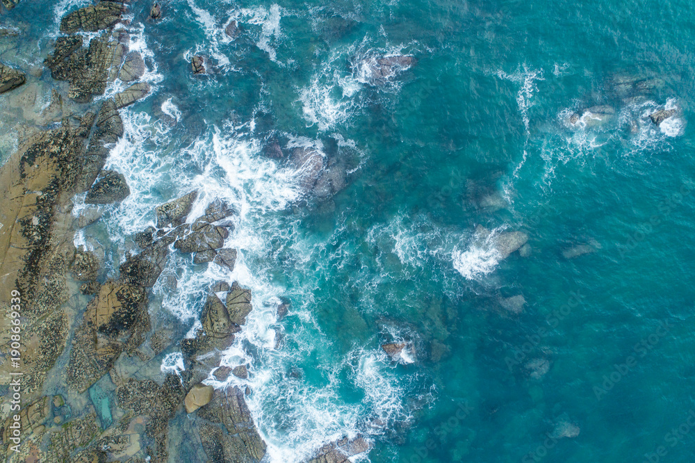 Obraz premium Aerial top down view of ocean waves crashing on rocks The Concept of Power