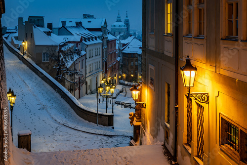Quadro su tela Winter morning with glowing gas lamps in snowy Prague - view of Lesser Town from