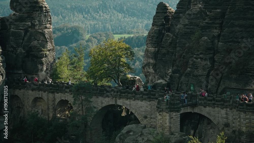 a slow-motion long focal range shot of tourists walking in the famous Bastei Bridge in Saxon Switzerland, Germany in a sunny summer day