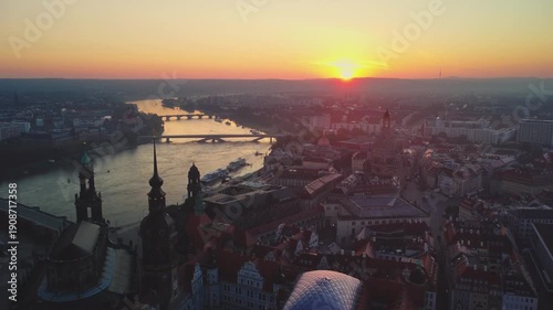 At dawn, an aerial view captures the river and the sun over the bridge in the distance, passing over Dresden Palace above the city's old town