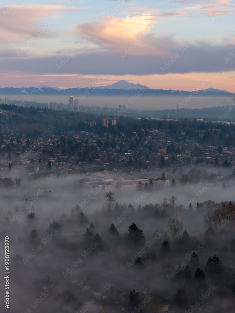 Fototapeta premium Sunrise Over Misty Burnaby Cityscape With Snowy Mountains In The Distance
