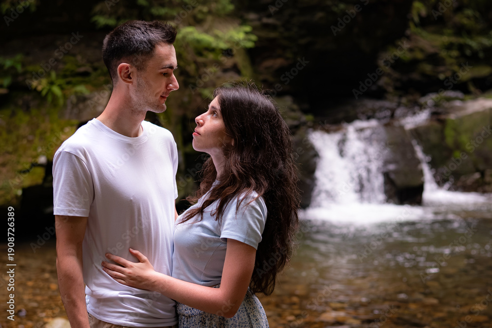 Fototapeta premium Young Couple Embracing Near Forest Waterfall