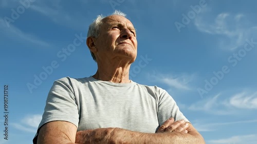 Older man standing outdoors with arms crossed under blue sky video frames.
