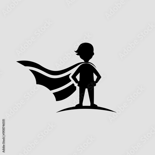 Confident young boy wearing superhero cape standing strong