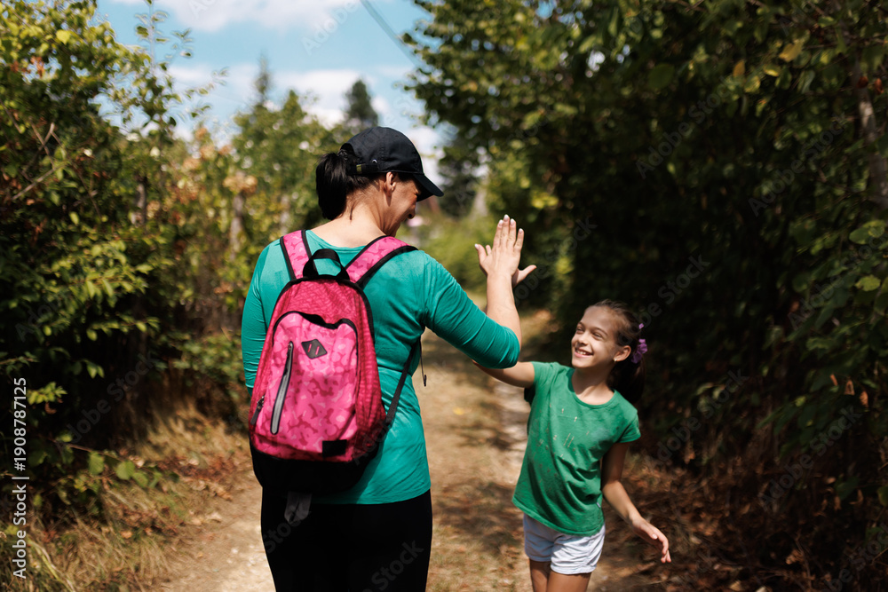 Naklejka premium Mother and daughter sharing a joyful moment during an outdoor hike in a forest trail