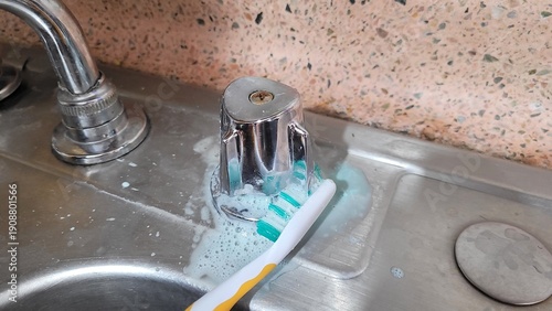 Photography Cleaning a kitchen sink faucet with a toothbrush and foamy soap for a sparkling