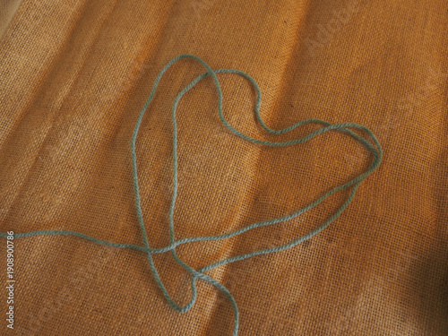 Foto Ball of yarn placed on brown burlap fabric, captured in warm natural light