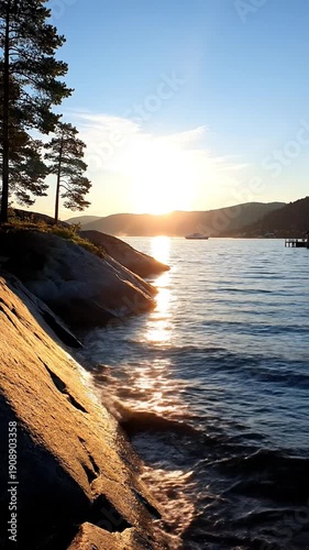 Golden sunset over rocky lake shore with boat and pine trees