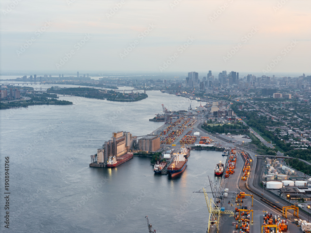 Obraz premium Aerial view of Montreal port with cargo containers, cranes and city skyline at sunset. g.