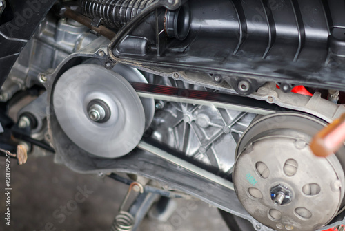Close up of a spinning motorcycle CVT belt and pulley system during engine testing in a workshop.