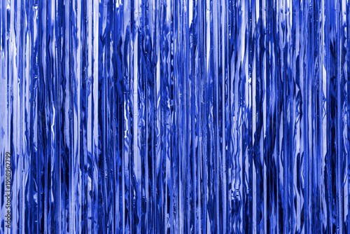 Blue foil strip background. Curtain hanging on wall. Festive, Christmas, New Year or anniversary party concept. Decorative wallpaper