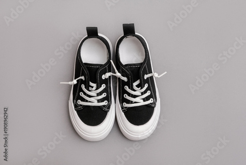 Child's black sneakers on the grey background. Fashion kids outfit. Flat lay, top view. Set of kids clothes and accessories for spring or autumn.