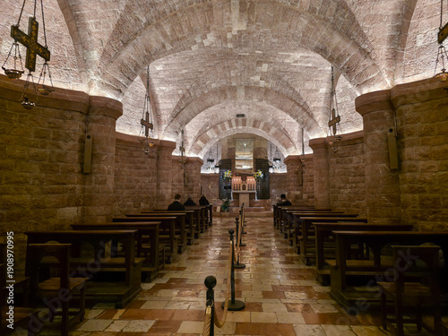 Interior of the Crypt of Saint Francis in Assisi with the stone tomb, Romanesque architecture, and pilgrims praying in the Lower Basilica, Umbria, Italy