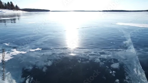 Bright Winter Sun Reflects on Vast Frozen Lake with Ice Cracks