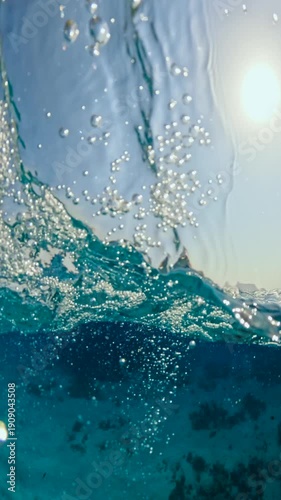 Vertical half underwater view of big waves and anchored diving yacht near coral reef in red sea