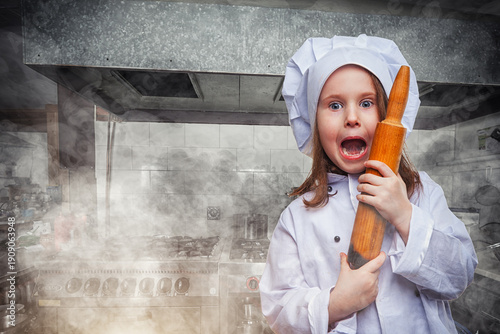 Little cute girl in chef uniform surprised and shocked looks on you.