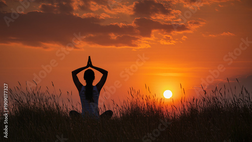 Yoga silhouette in Anjali Mudra at sunset, surrounded by tall grass, with warm orange and red skies, evoking serenity, mindfulness, and spiritual calm.