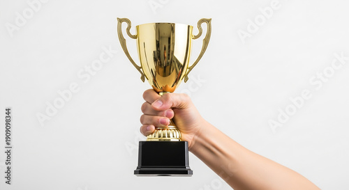 Hand triumphantly holding a golden trophy cup, celebrating victory, success, and achievement in a competition.