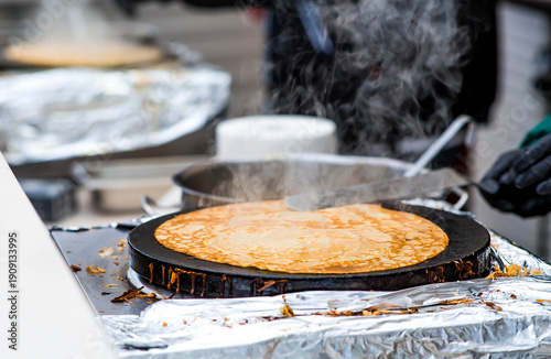 Cooking pancakes outdoors in a close-up with rising steam, which is timed to coincide with the arrival of spring and the Maslenitsa holiday.