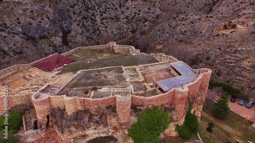 Historic citadel ruins in Albarracín, showing fortified stone walls atop a rocky cliff within the medieval landscape of Aragon, Spain