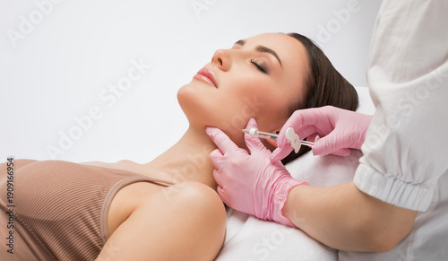 Cosmetologist makes rejuvenating anti wrinkle injections on the face of a beautiful woman. Female aesthetic cosmetology in a beauty salon.